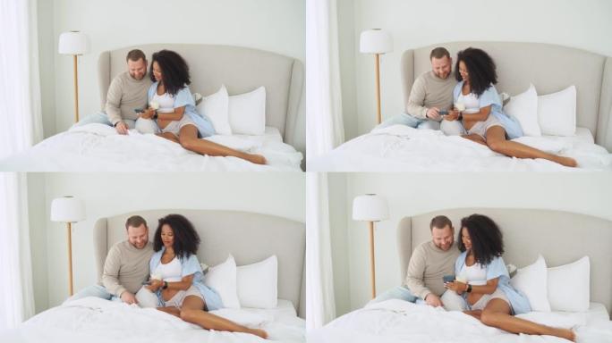 怀孕的夫妇在床上用手机。女人喝牛奶看着智能手机中的照片。怀孕网上购物，社交媒体，回忆。