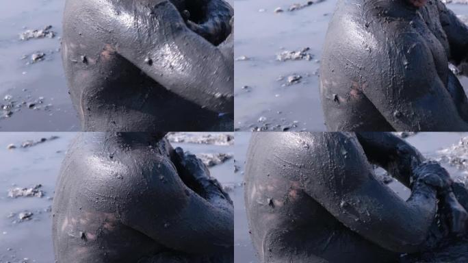 一名男子在他的身体上涂抹愈合泥。对身体和皮肤有益效果。医疗保健。死海中的盐和泥