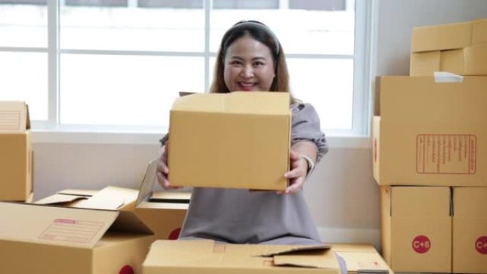Asian woman holding parcel box and looking and han