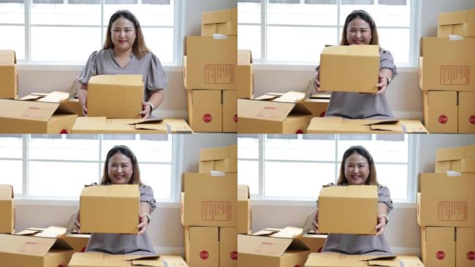 Asian woman holding parcel box and looking and han