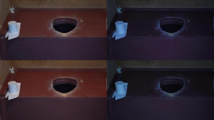后院的农村木制厕所。打开和关闭电，灯泡。关闭视图。前景中的一卷卫生纸。