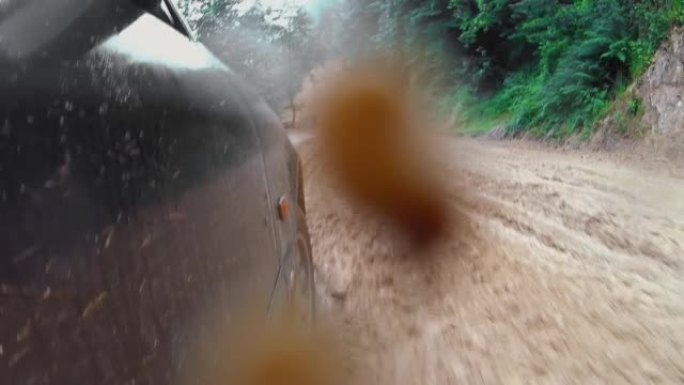 汽车沿着被雨水冲刷的道路行驶，相机拍摄了汽车的车轮