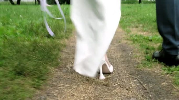 穿着漂亮鞋子的走路新娘和新郎的脚。