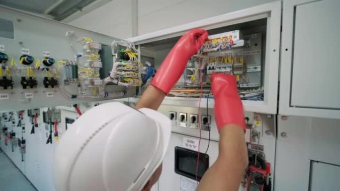 电气工程师在主配电系统室中检查负载中心机柜或消费单元前部的电流电压和过载，以进行维护。