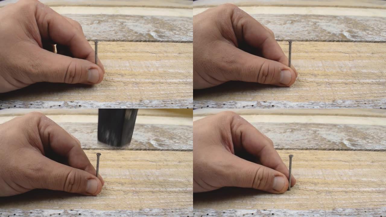 用手将钉子锤入老式木质表面木板桌。