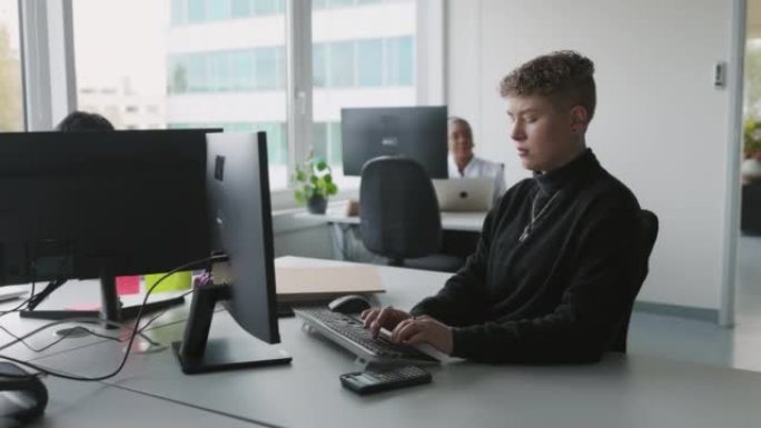 年轻的非二进制医疗办公室管理员在办公室使用计算机