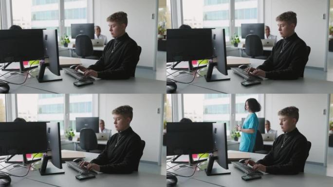 年轻的非二进制医疗办公室管理员在办公室使用计算机