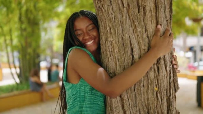 非裔美国妇女在公园里微笑着自信的拥抱树