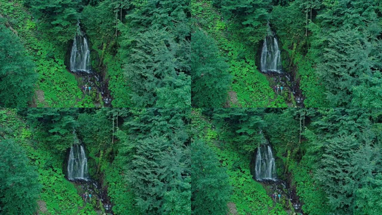 在高海拔森林中迷路的游客团队进入空地瀑布发出求救信号。从悬崖上掉下来的溪流的鸟瞰图。