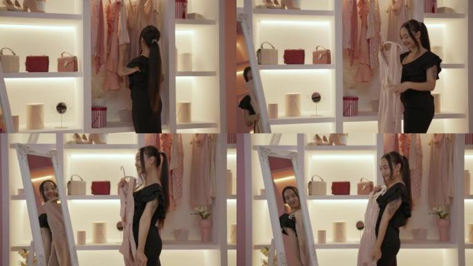 穿着黑色连衣裙的亚洲女性选择新衣服套装站在衣柜里的镜子前。试穿新衣服的女士。
