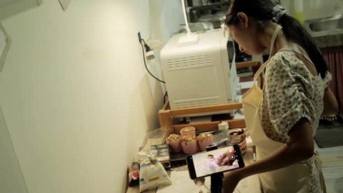 在家厨房用智能手机制作巧克力大福麻糬(日本小吃)视频的女孩，生活理念。