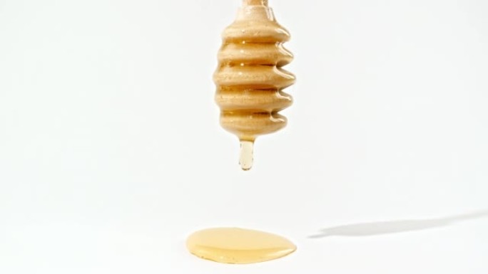 蜂蜜滴到蜂蜜北斗七星上。液体蜂蜜在孤立的白色背景上流动。健康食品概念。垂直视频。宏观拍摄。