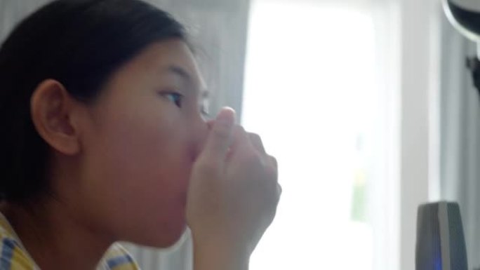 亚洲少女在家玩网络游戏和台式电脑流媒体时吃切片苹果，生活方式概念。