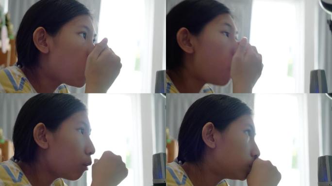亚洲少女在家玩网络游戏和台式电脑流媒体时吃切片苹果，生活方式概念。
