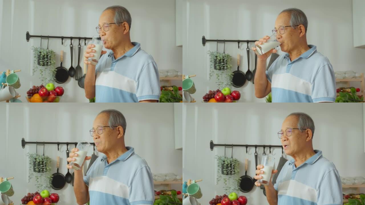 亚洲高级成熟男性在家厨房喝一杯牛奶。有吸引力的年长的祖父在早上醒来后抱着一杯牛奶，在家里做保健。