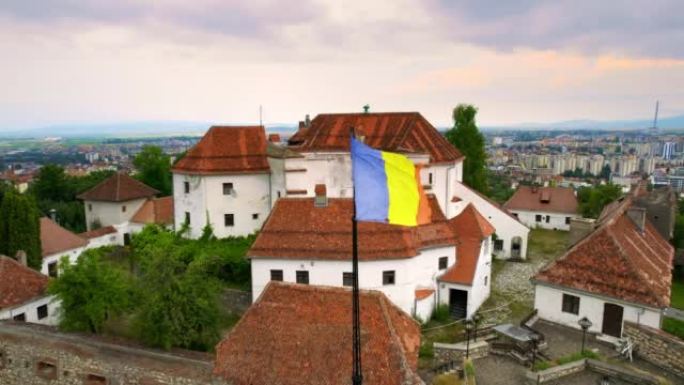 罗马尼亚布拉索夫城堡的空中无人机视图。中世纪的堡垒和国旗在山顶上。周围的建筑物和绿树
