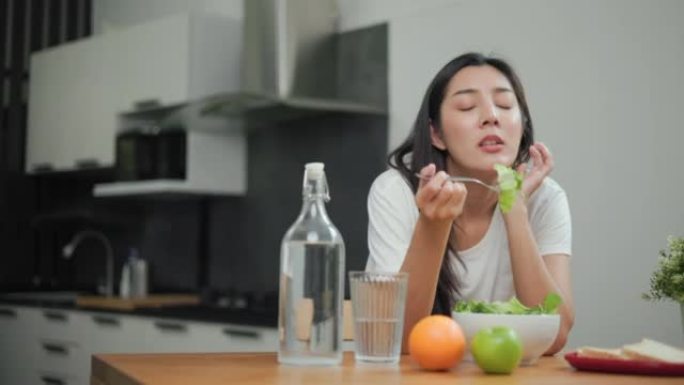 不快乐的女性在餐桌上寻找减肥饮食和健康的有机蔬菜沙拉。疲倦的女人不喜欢在厨房吃无聊的食物健康沙拉早餐
