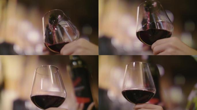 在餐厅的餐桌上，一位女调酒师在酒杯中供应红酒的特写镜头。
