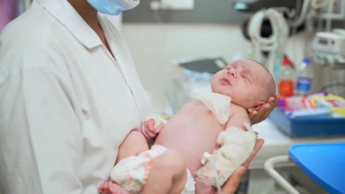 年轻的女儿科医生护士在NICU病房抱着一名新生婴儿