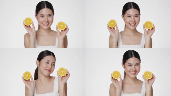 亚洲女性对完美清洁健康的皮肤感到满意。可爱的女模特干净清新的皮肤拿着一个橙色。富有表现力的面部表情。