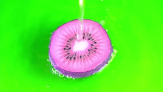 水倒在紫色色调多汁的猕猴桃绿色背景慢动作特写。猕猴桃切片水溅，多汁的背景，异国水果。制作水果鸡尾酒，