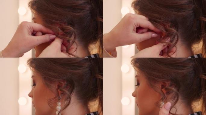 女性双手的特写镜头将珍珠耳环插入女孩的耳朵。