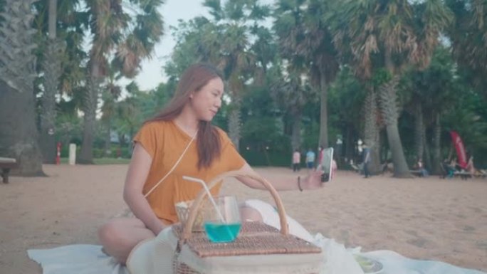 年轻女子在海边用包和毯子野餐