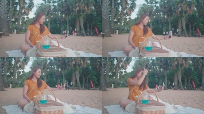 年轻女子在海边用包和毯子野餐