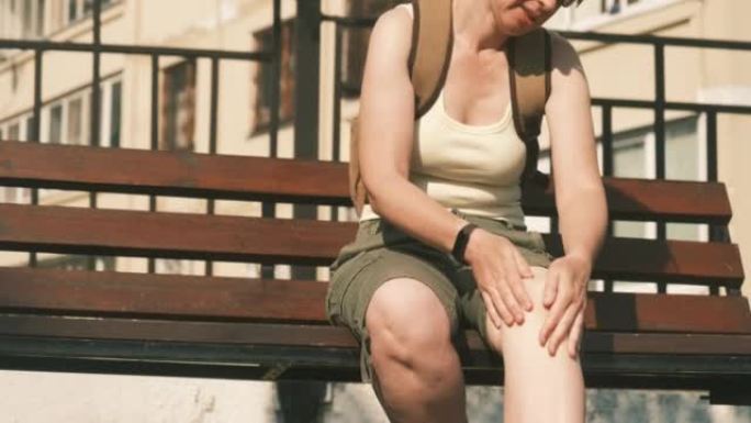 活跃的成熟女人坐在长凳上按摩膝盖