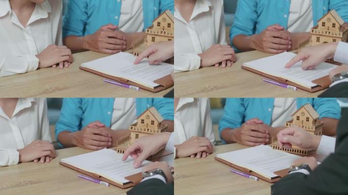 房地产经纪人的手指着购房合同纸的特写由于向一对夫妇解释