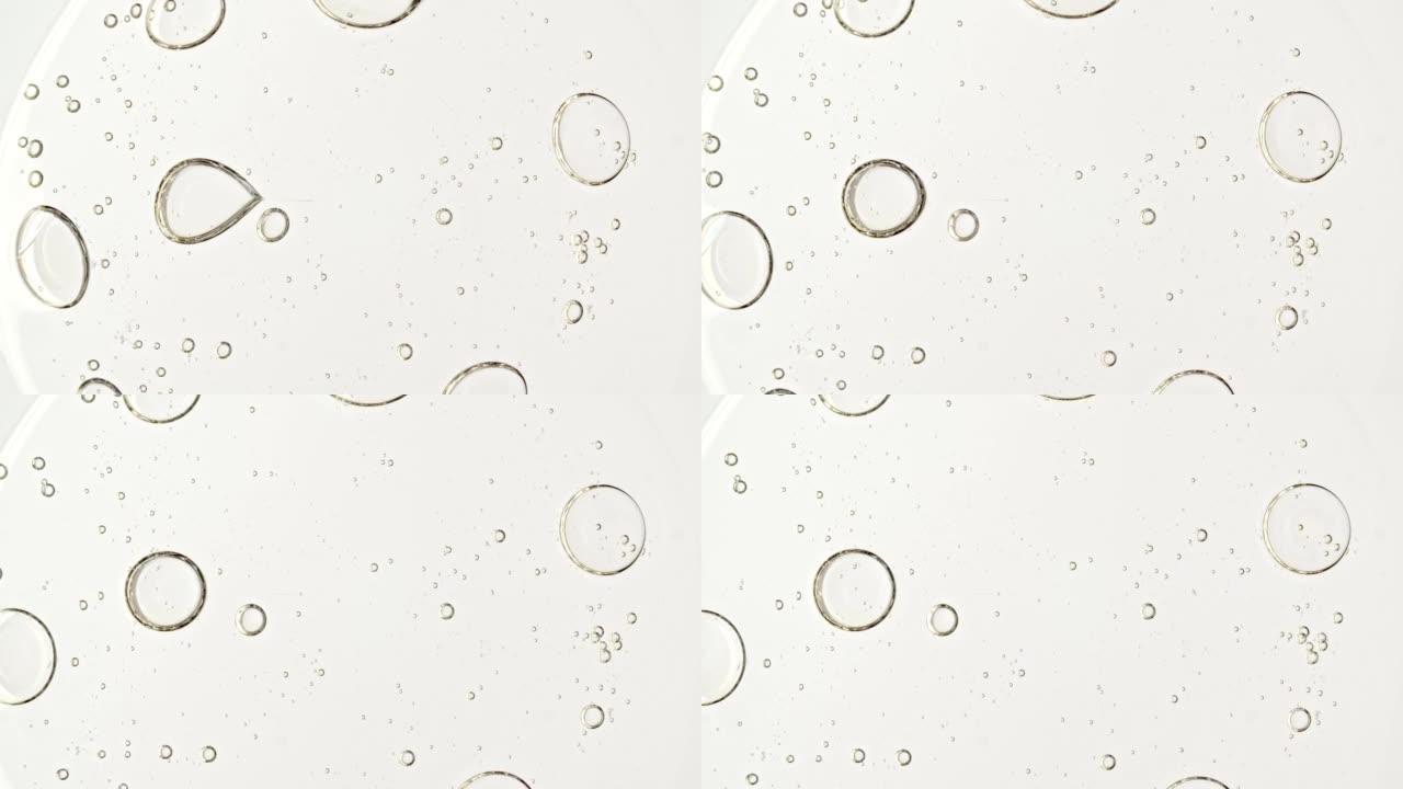 透明化妆品凝胶流体，分子气泡油分布在白色背景上。天然有机化妆品、药物的宏观拍摄。生产特写。慢动作