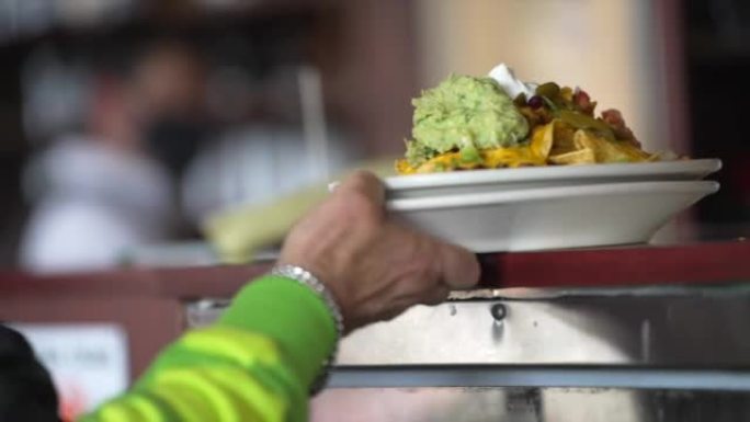 server grabs food nacho order off counter