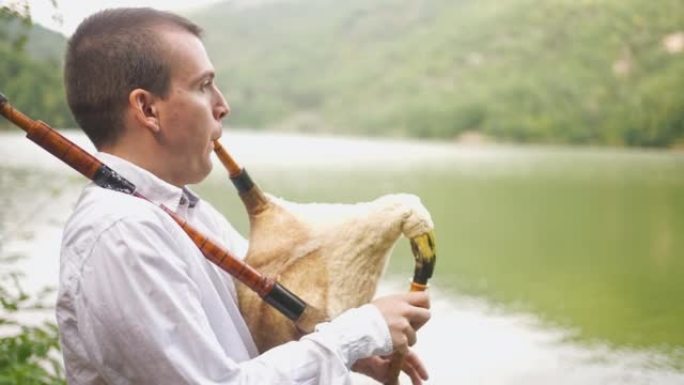 森林湖的平静使风笛的声音在男性民间音乐家演奏时突出