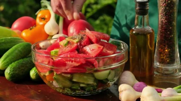 盐蔬菜沙拉慢动作。在户外做蔬菜沙拉。用新鲜的生蔬菜烹饪沙拉-西红柿，黄瓜，蔬菜，胡椒，葱，洋葱，橄榄