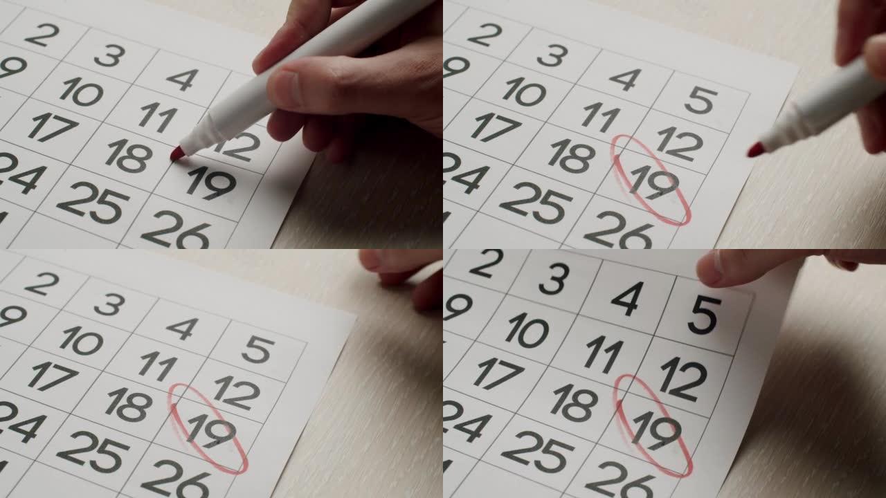 男人的手用红笔在纸质日历上写下第19天。