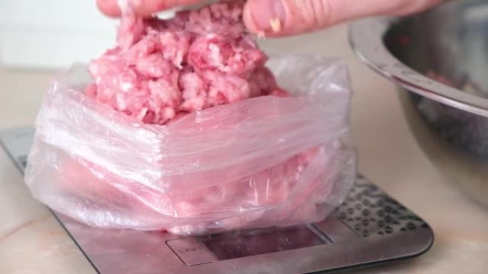 一名男子将猪肉和牛肉末放在袋装的秤上，以存放在冰箱中。