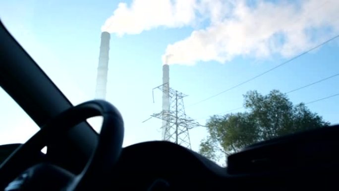 乘坐汽车经过白色蒸汽自然污染的工厂管道