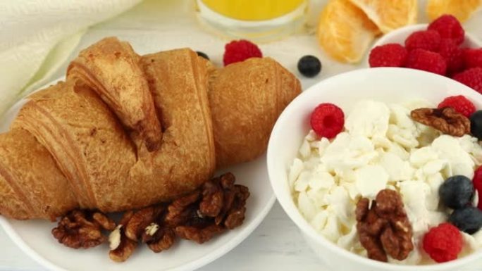 早餐配奶酪和羊角面包。早餐桌上有奶酪、浆果和羊角面包。早餐的俯视图