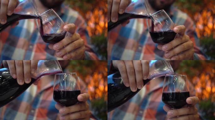 男人手在玻璃水瓶红酒中的特写镜头。