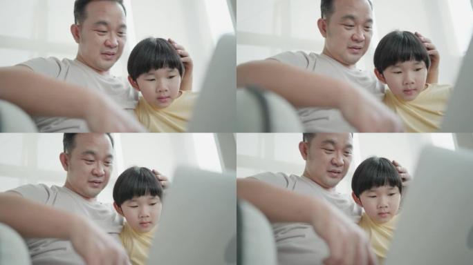 细心的亚洲父亲照顾，教导和帮助可爱的儿子发挥想象力，并在笔记本电脑上学习社交媒体知识。家庭享受在家客