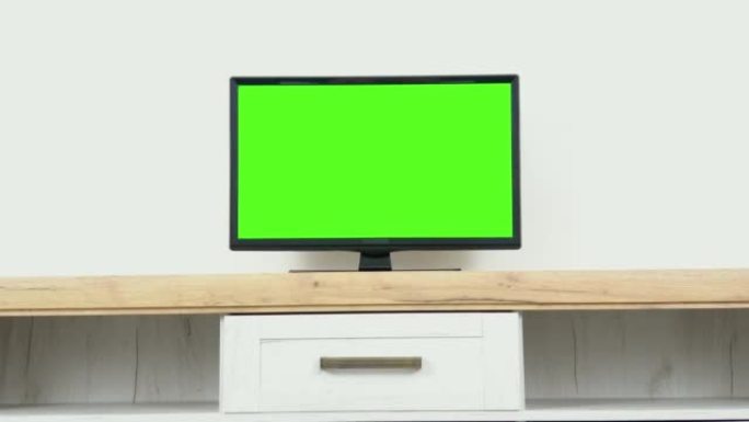 家里空荡荡的客厅，显示器上有色度键占位符。时尚的公寓内部配有电视和绿屏模拟gisplay站在电视架上