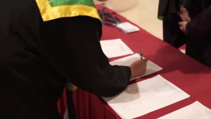 一名女学生在留言簿上签名，用笔参加毕业典礼。
