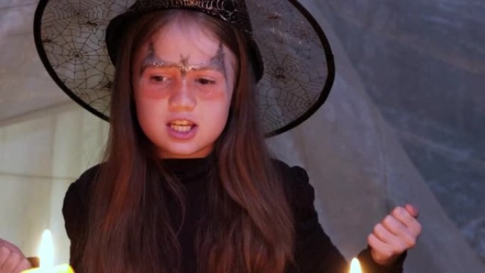 疯狂的小女巫在烛光下在万圣节之夜读咒语