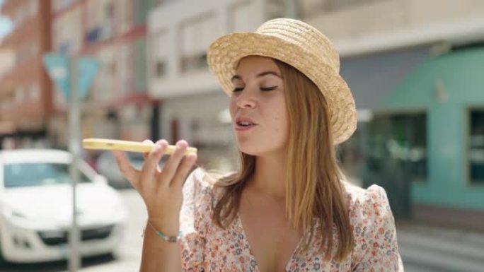 戴着夏季帽子的年轻女性游客在街上用智能手机聊天