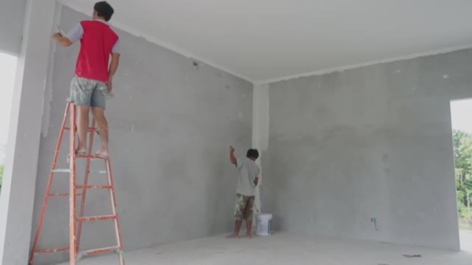 画家粉刷房子的墙壁。