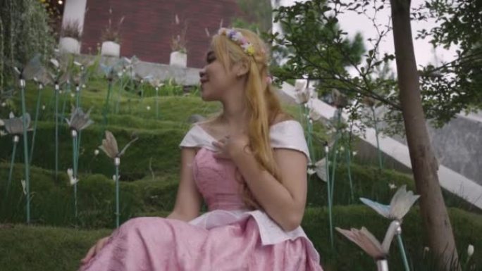 一位穿着粉红色连衣裙的公主独自一人在花园里玩郁金香花