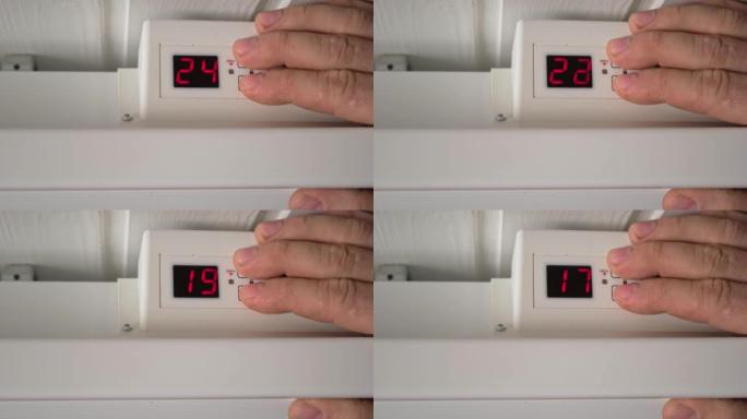男子降低电加热器的温度。特写。由于供暖成本价格上涨，调节散热器上的恒温器以节省能源。节能。摄氏单位。