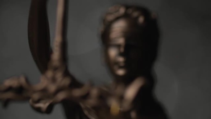 被蒙住眼睛的女神手持象征公正和权力的剑，缓慢旋转的国际青铜法律符号