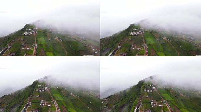 在带有雾的局部山脉上飞越村庄