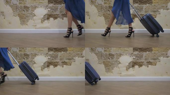女孩穿着蓝色连衣裙和黑色高跟凉鞋去度假，在房间里滚动一个蓝色手提箱。侧视图、特写、慢动作